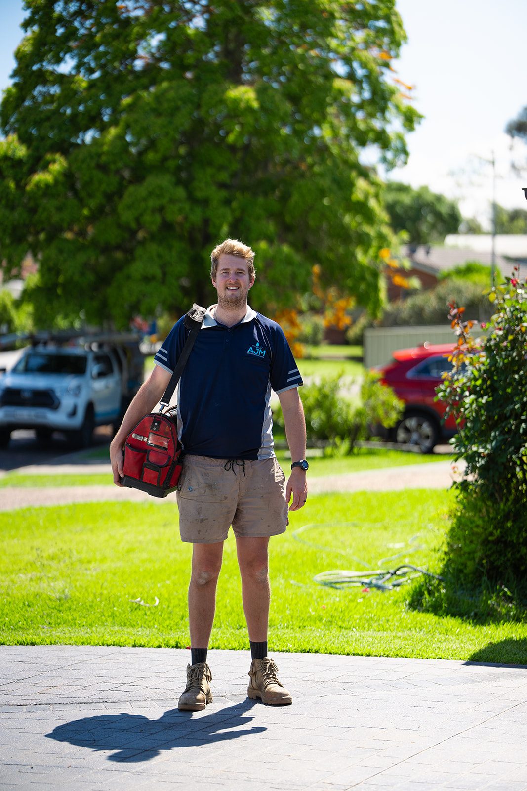 Aaron with his tool bag on a front lawn
