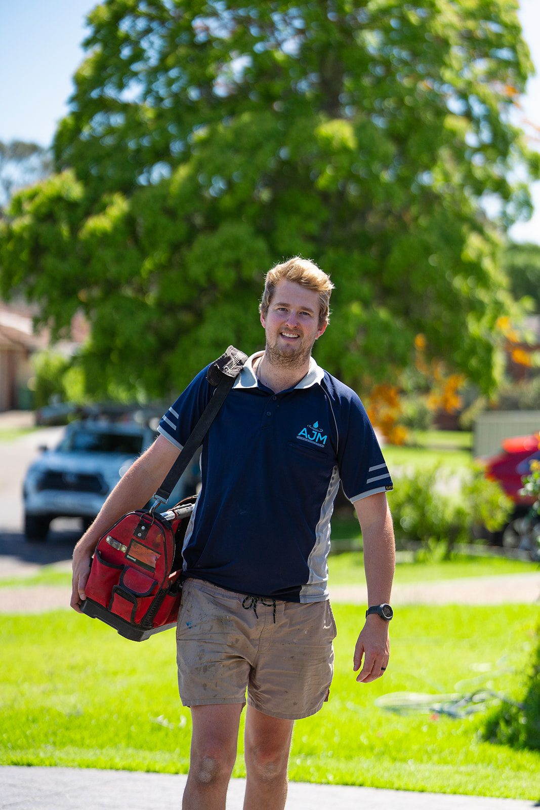 Aaron smiling with his tool bag in a Sydney street