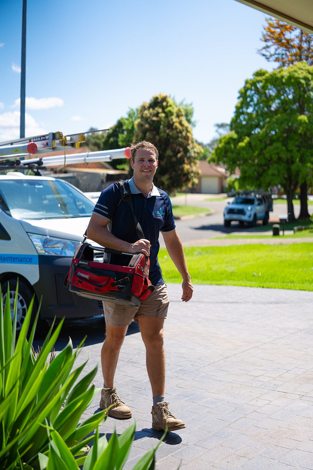Aaron from AJM Plumbing Solutions with his tool bag on a driveway